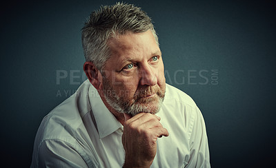 Buy stock photo Studio shot of a handsome mature businessman looking thoughtful while sitting down against a dark background