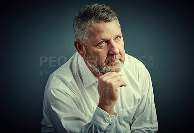 Buy stock photo Studio shot of a handsome mature businessman looking thoughtful while sitting down against a dark background