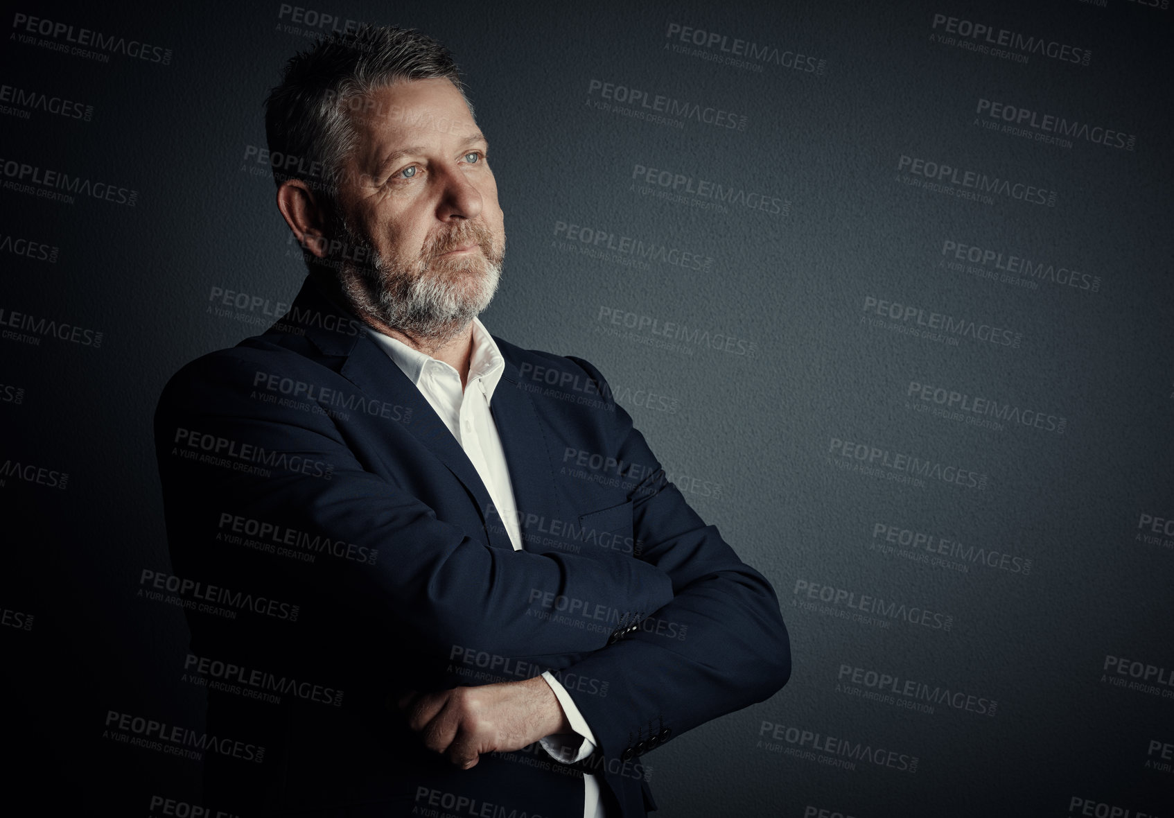 Buy stock photo Studio shot of a handsome mature businessman looking thoughtful while standing with his arms folded against a dark background