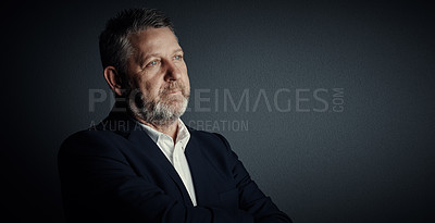 Buy stock photo Studio shot of a handsome mature businessman looking thoughtful while standing against a dark background