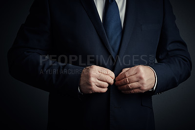 Buy stock photo Studio shot of an unrecognizable mature businessman buttoning his jacket standing against a dark background