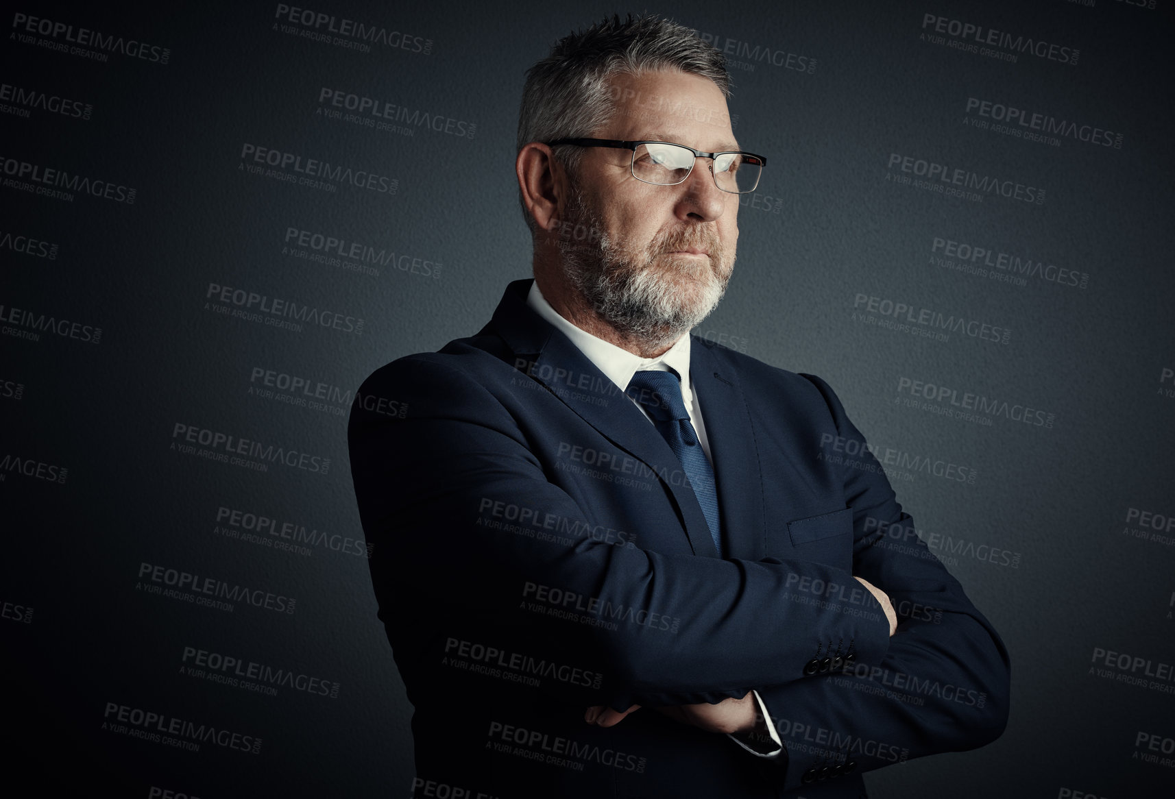 Buy stock photo Studio shot of a handsome mature businessman looking thoughtful while standing with his arms folded against a dark background