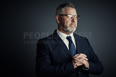 Buy stock photo Studio shot of a handsome mature businessman looking thoughtful while standing against a dark background
