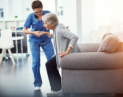 Buy stock photo Full length shot of a young female nurse helping her senior patient up from a chair in the old age home
