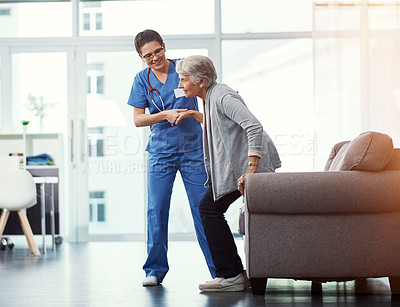 Buy stock photo Full length shot of a young female nurse helping her senior patient up from a chair in the old age home