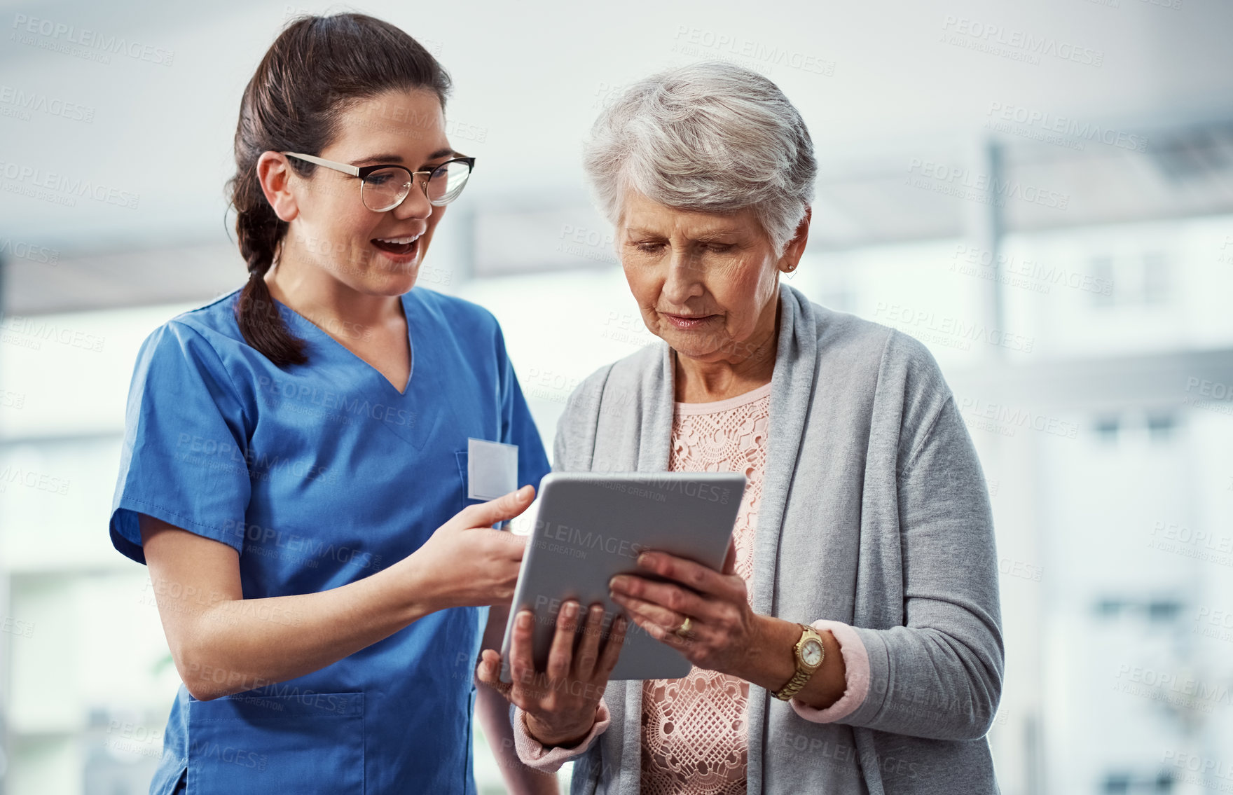 Buy stock photo Cropped shot of a young female nurse and her senior patient looking at a tablet in the old age home