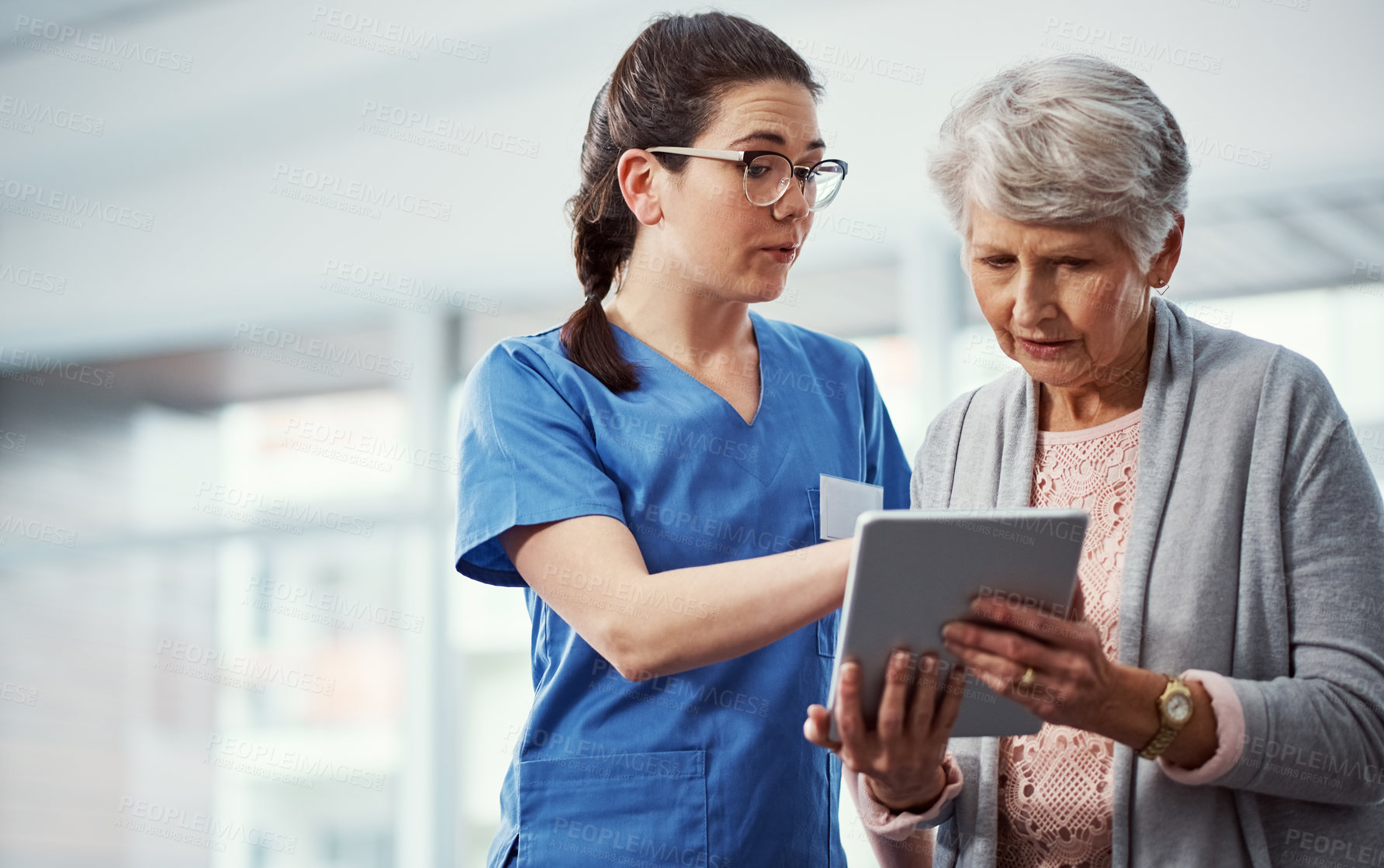 Buy stock photo Cropped shot of a young female nurse and her senior patient looking at a tablet in the old age home