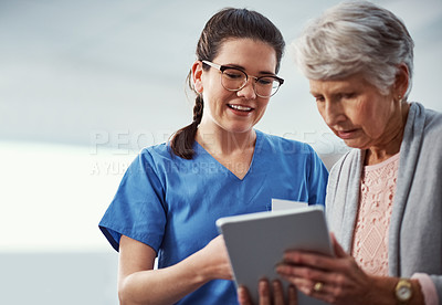 Buy stock photo Cropped shot of a young female nurse and her senior patient looking at a tablet in the old age home
