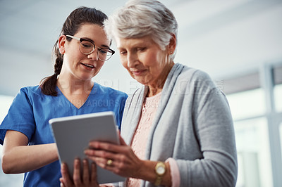 Buy stock photo Cropped shot of a young female nurse and her senior patient looking at a tablet in the old age home