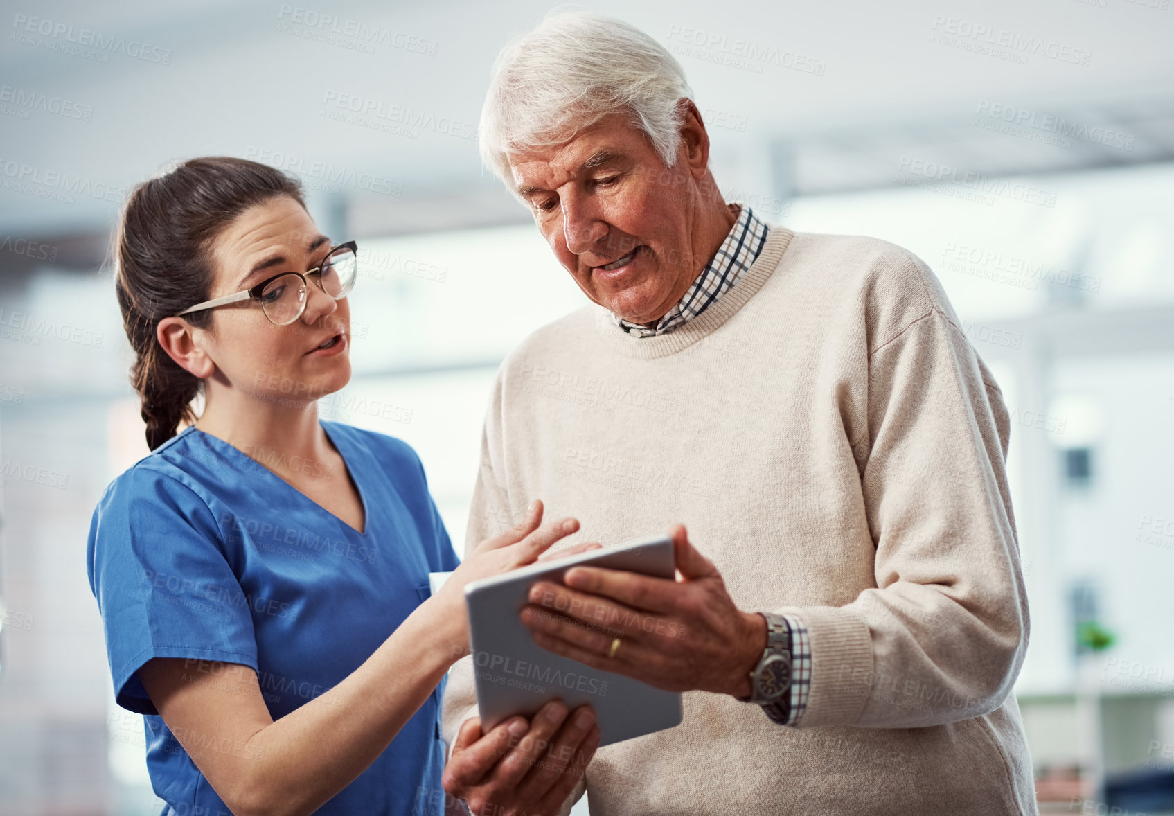 Buy stock photo Cropped shot of a young female nurse and her senior patient looking at a tablet in the old age home