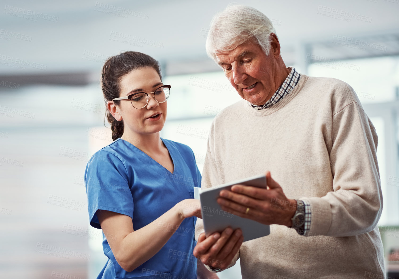 Buy stock photo Cropped shot of a young female nurse and her senior patient looking at a tablet in the old age home