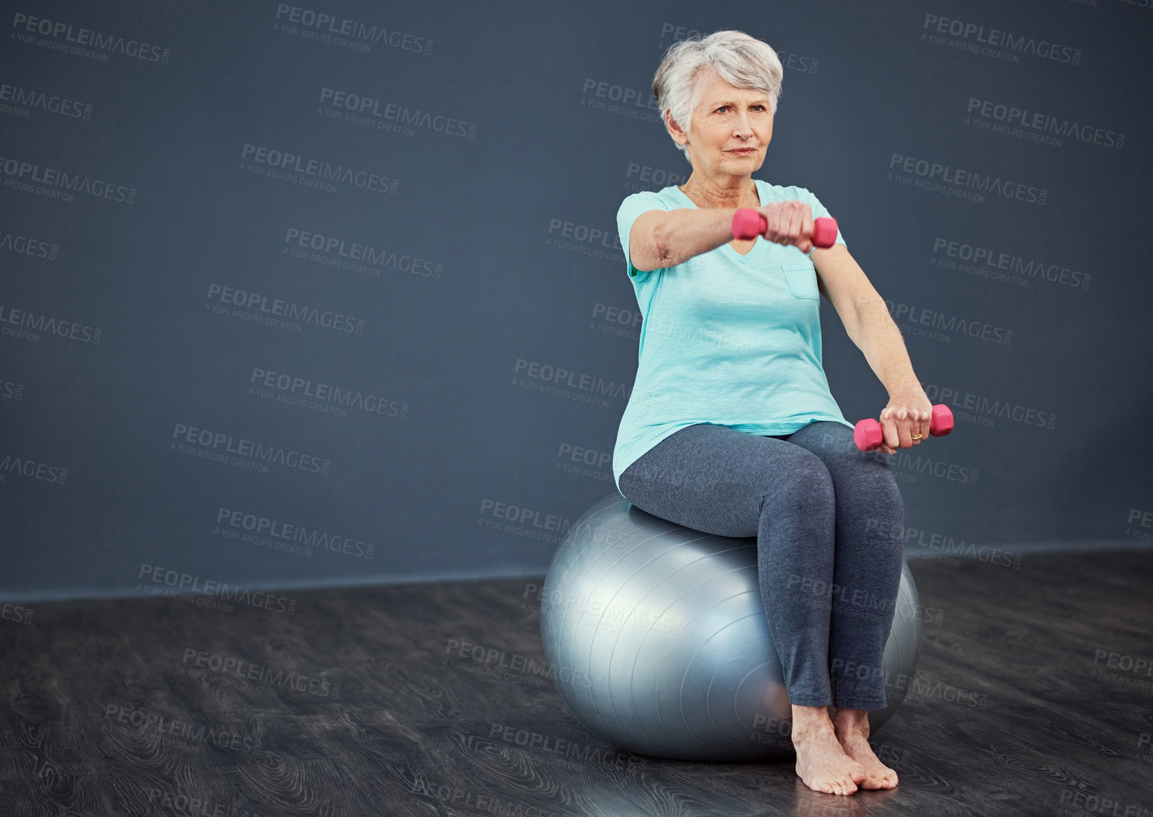 Buy stock photo Full length shot of a senior woman working out with dumbbells while sitting on an exercise ball