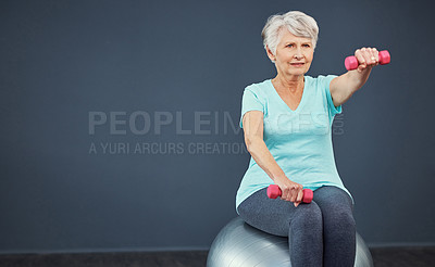 Buy stock photo Cropped shot of a senior woman working out with dumbbells while sitting on an exercise ball