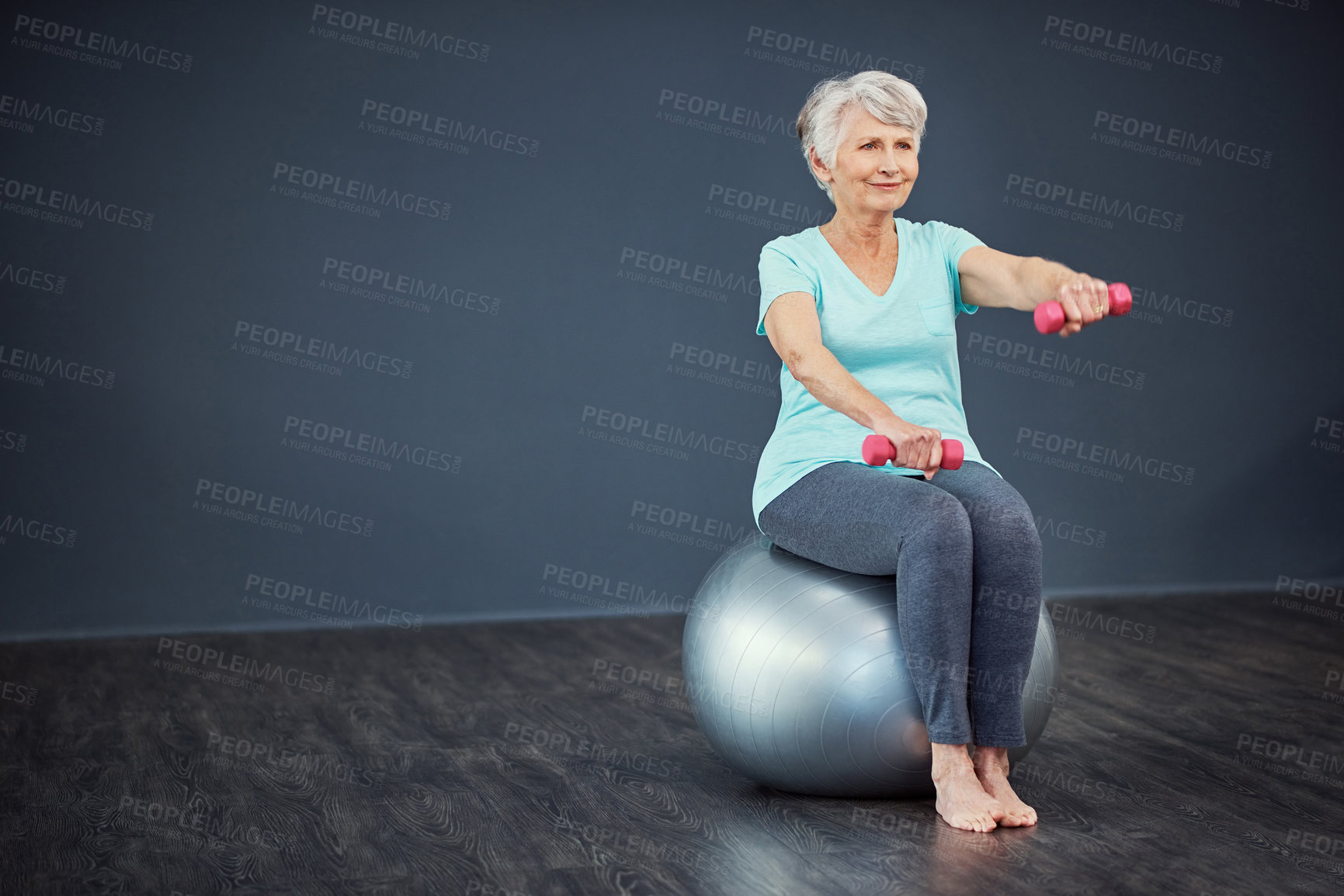 Buy stock photo Full length shot of a senior woman working out with dumbbells while sitting on an exercise ball