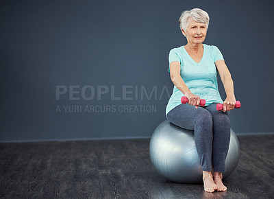Buy stock photo Full length shot of a senior woman working out with dumbbells while sitting on an exercise ball