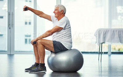 Buy stock photo Full length shot of a senior man working out with dumbbells while sitting on an exercise ball