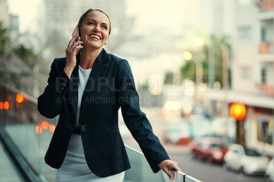 Buy stock photo Cropped shot of an attractive mature businesswoman using her cellphone while standing on the balcony of her office