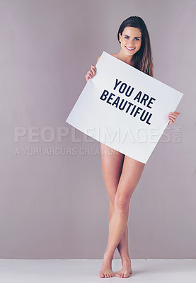 Buy stock photo Studio portrait of an attractive young woman holding a sign that reads “you are beautiful” against a pink background