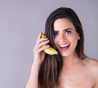 Buy stock photo Studio portrait of an attractive young woman pretending to use a banana as a phone against a purple background