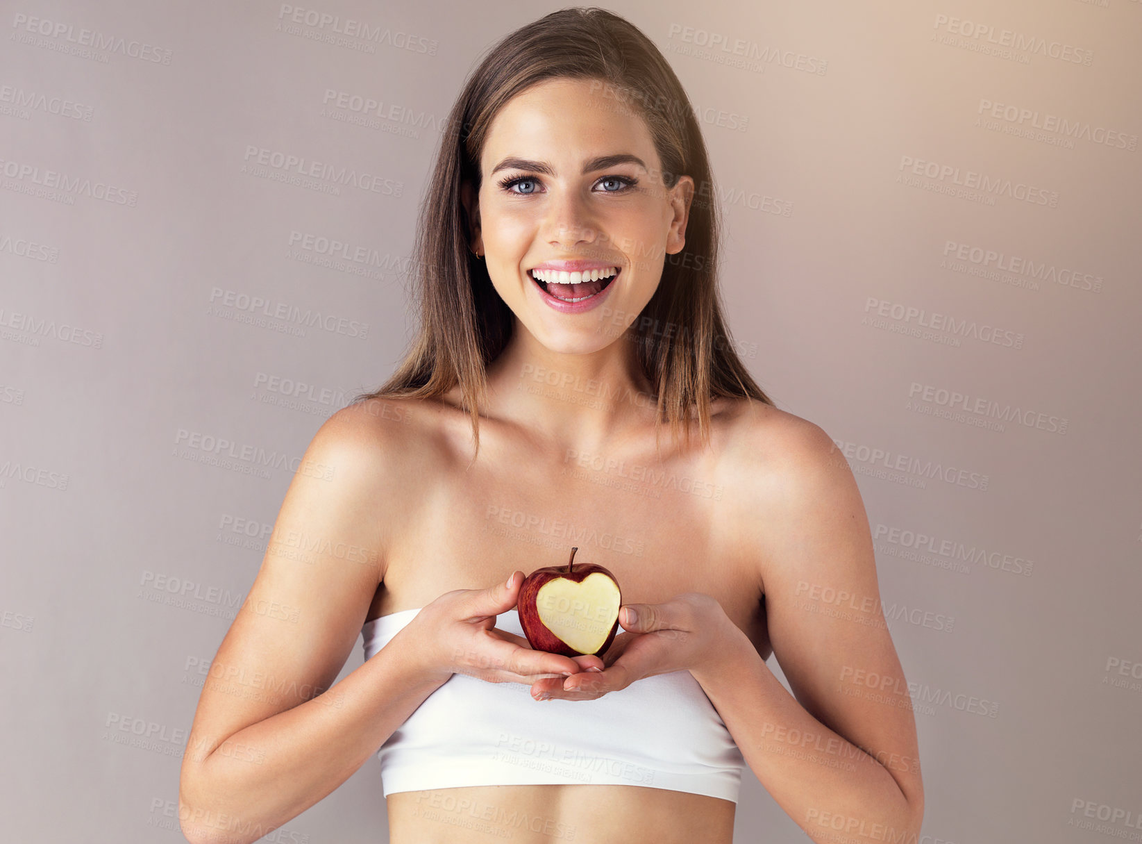 Buy stock photo Happy, apple and portrait of woman in studio for health, wellness and diet snack for nutrition. Heart, vitamins and female person with bite in organic, fresh or natural fruit by gray background.