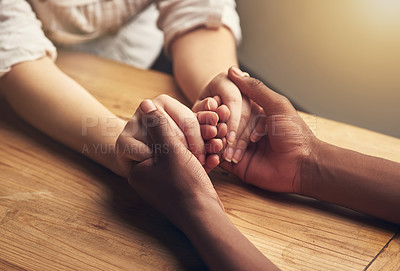 Buy stock photo Love, comfort and couple holding hands for support, unity and compassion by wood table. Empathy, care and interracial friends with affection in cancer grief together for connection, bond and trust