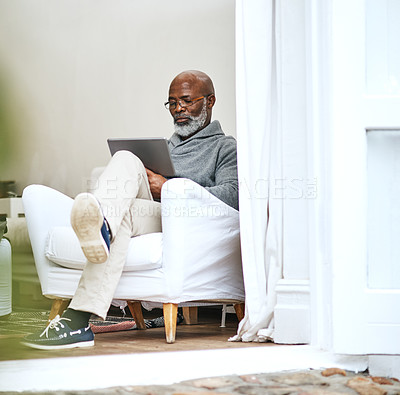 Buy stock photo Senior, man and home with tablet in chair, browsing internet and reading blog or news on social media in apartment. Tech, relax and living room for website, app and connection for email in house