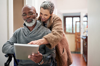 Buy stock photo Cropped shot of an affectionate senior couple using a tablet at home with the man sitting in a wheelchair