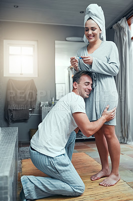 Buy stock photo Shot of a young couple looking happy after taking a pregnancy test at home 