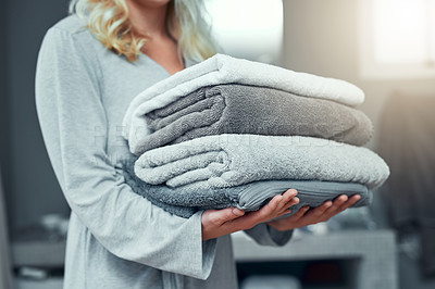 Buy stock photo Closeup shot of an unrecognizable woman carrying a pile of towels while doing laundry at home
