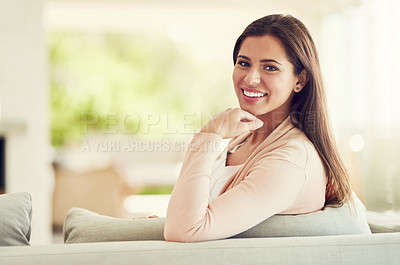 Buy stock photo Portrait of a cheerful young woman relaxing on the sofa at home while looking into the camera