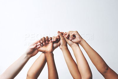 Buy stock photo Studio shot of a group of unrecognizable people holding each others' thumbs while their hands are raised