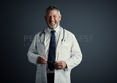 Buy stock photo Studio portrait of a handsome mature male doctor standing against a dark background