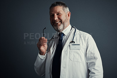 Buy stock photo Studio portrait of a handsome mature male doctor standing against a dark background