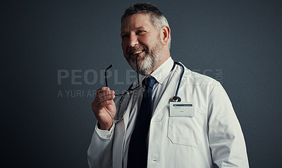 Buy stock photo Studio shot of a handsome mature male doctor looking thoughtful while standing against a dark background