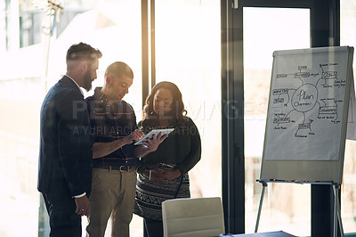 Buy stock photo Shot of a focused group of businesspeople having a discussion while using a digital laptop in a boardroom