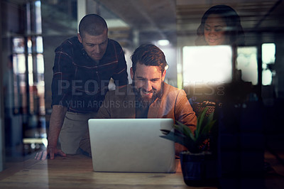 Buy stock photo Shot of a group of work colleagues working together on a laptop and exchanging ideas in the office