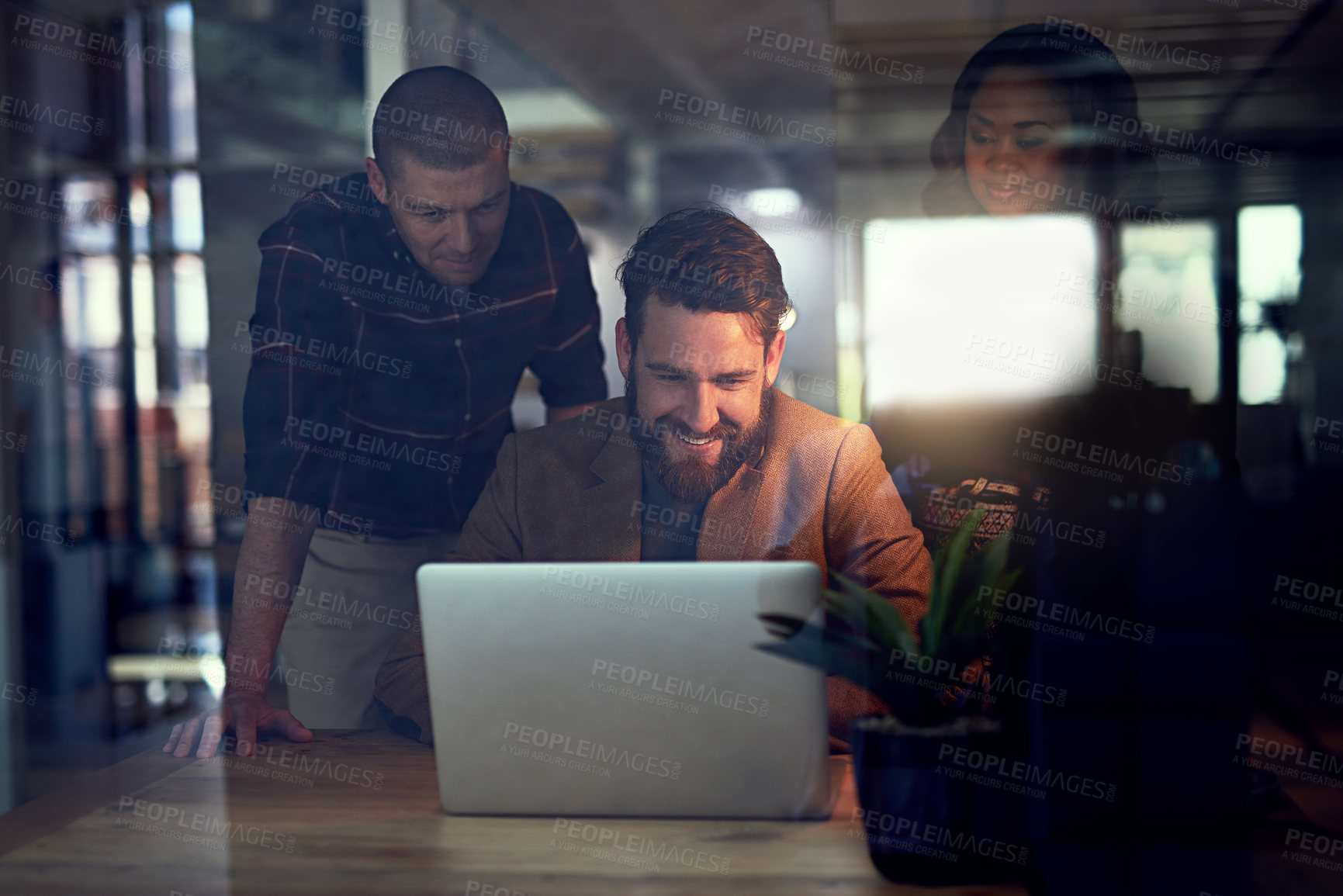 Buy stock photo Shot of a group of work colleagues working together on a laptop and exchanging ideas in the office