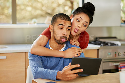 Buy stock photo Shot of a happy young couple using a digital tablet to take selfies at home