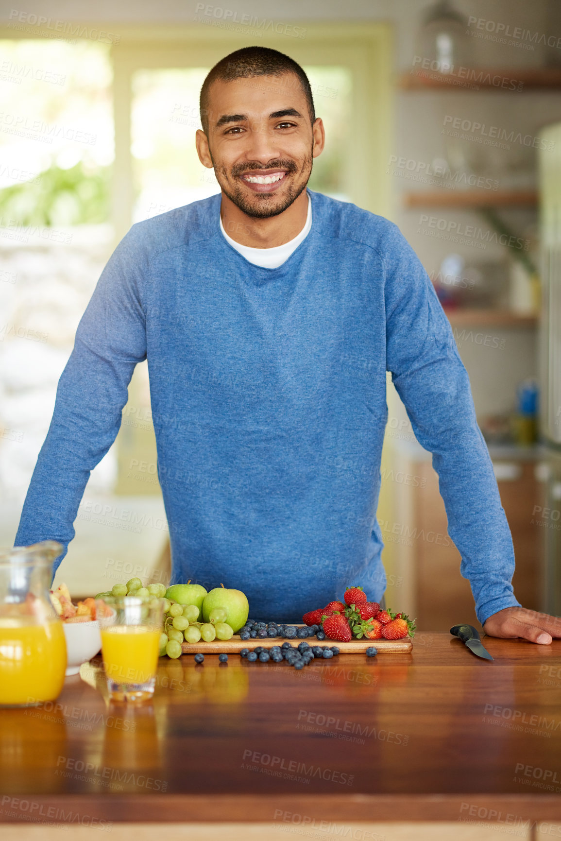 Buy stock photo Portrait of a happy young man preparing a healthy snack at home