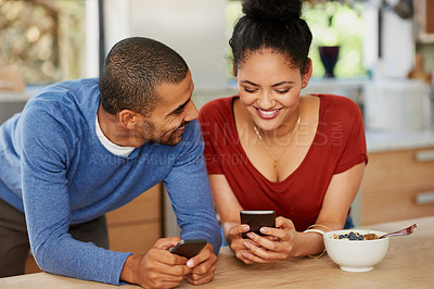 Buy stock photo Shot of a happy young couple using their smartphones together at home