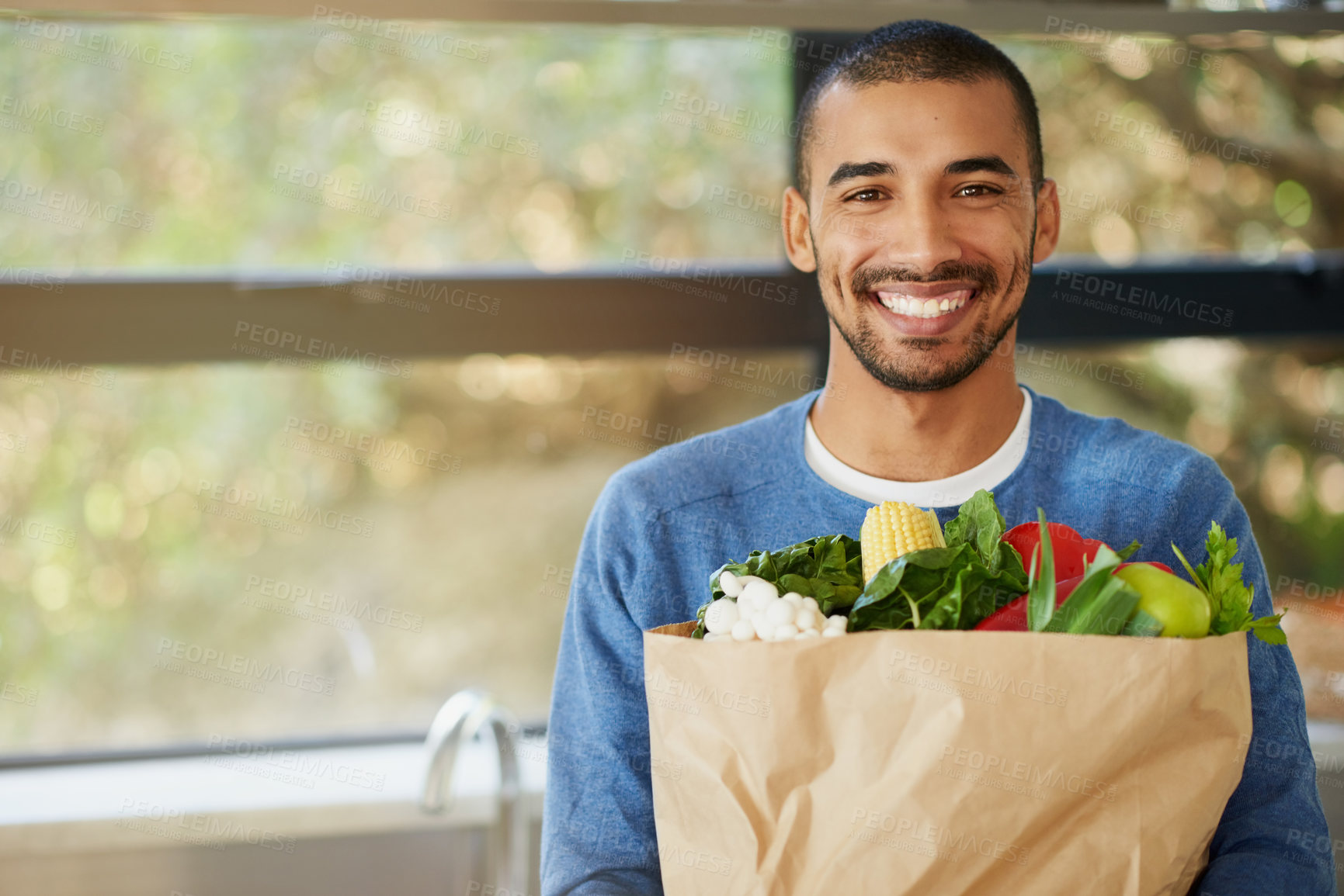Buy stock photo Portrait of a happy young man holding a bag full of healthy vegetables at homee