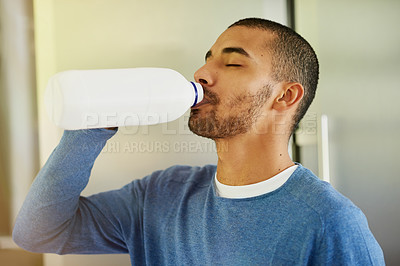 Buy stock photo Shot of a young man drinking milk from the bottle at home