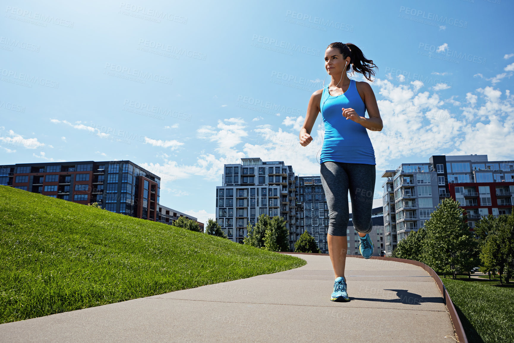 Buy stock photo Shot of a young woman listening to music while out running