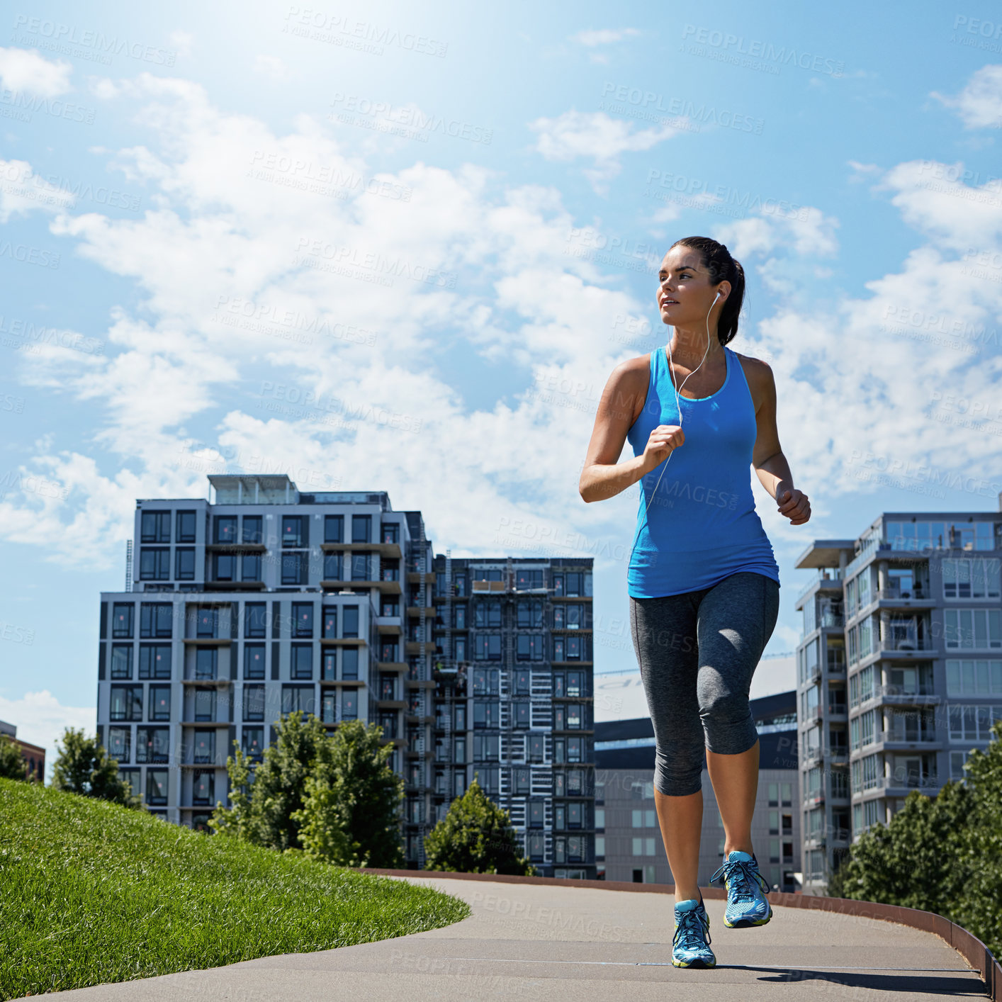 Buy stock photo Shot of a young woman listening to music while out running