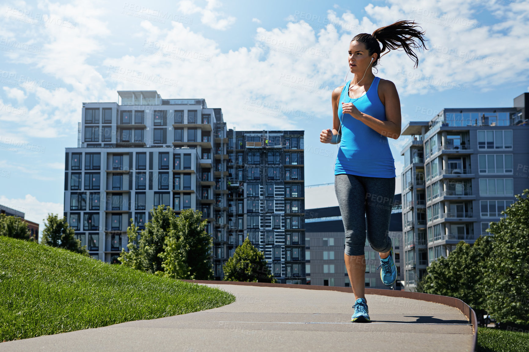 Buy stock photo Shot of a young woman listening to music while out running