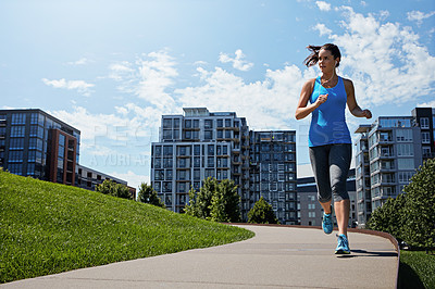 Buy stock photo Shot of a young woman listening to music while out running