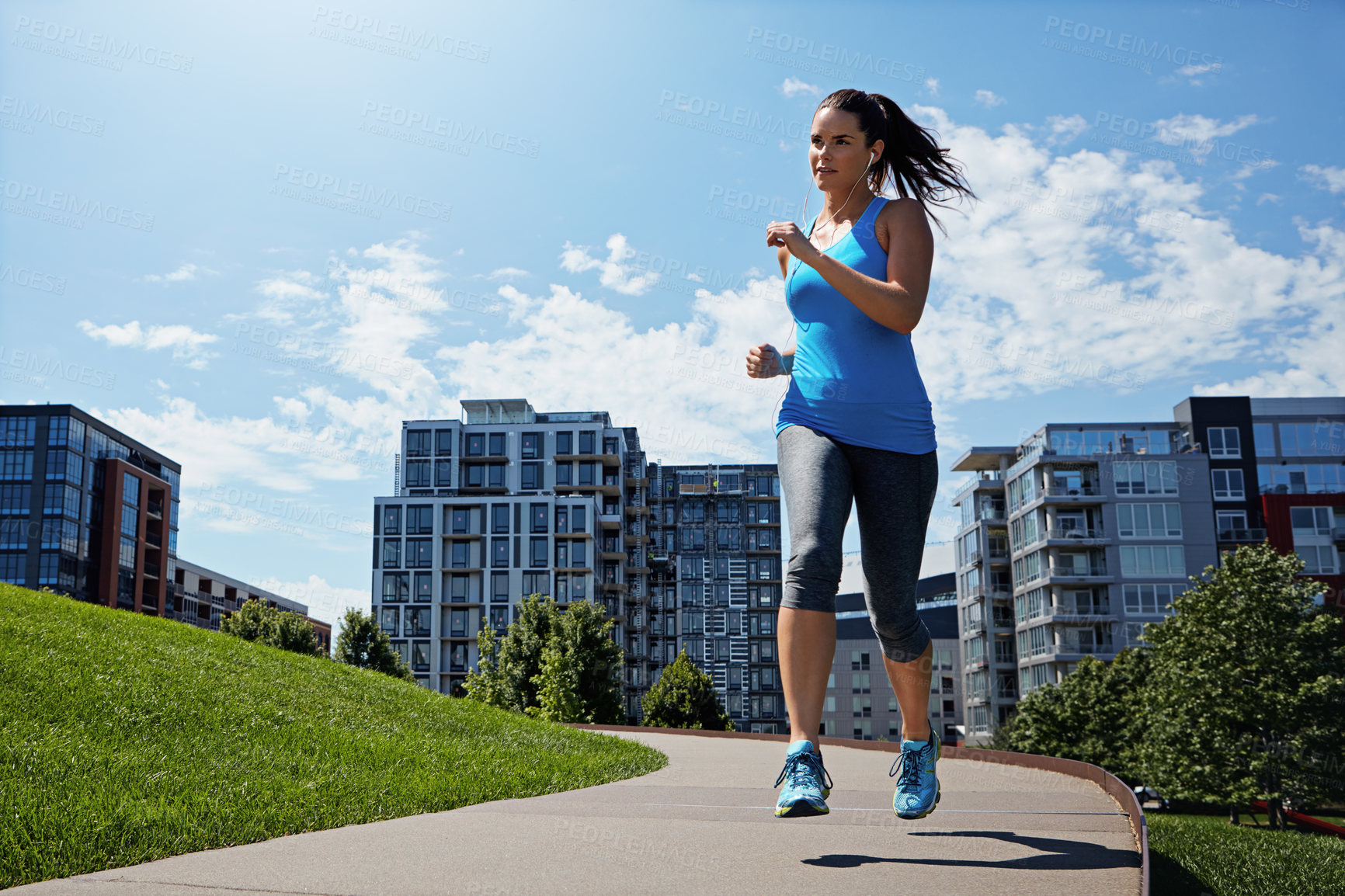 Buy stock photo Shot of a young woman listening to music while out running