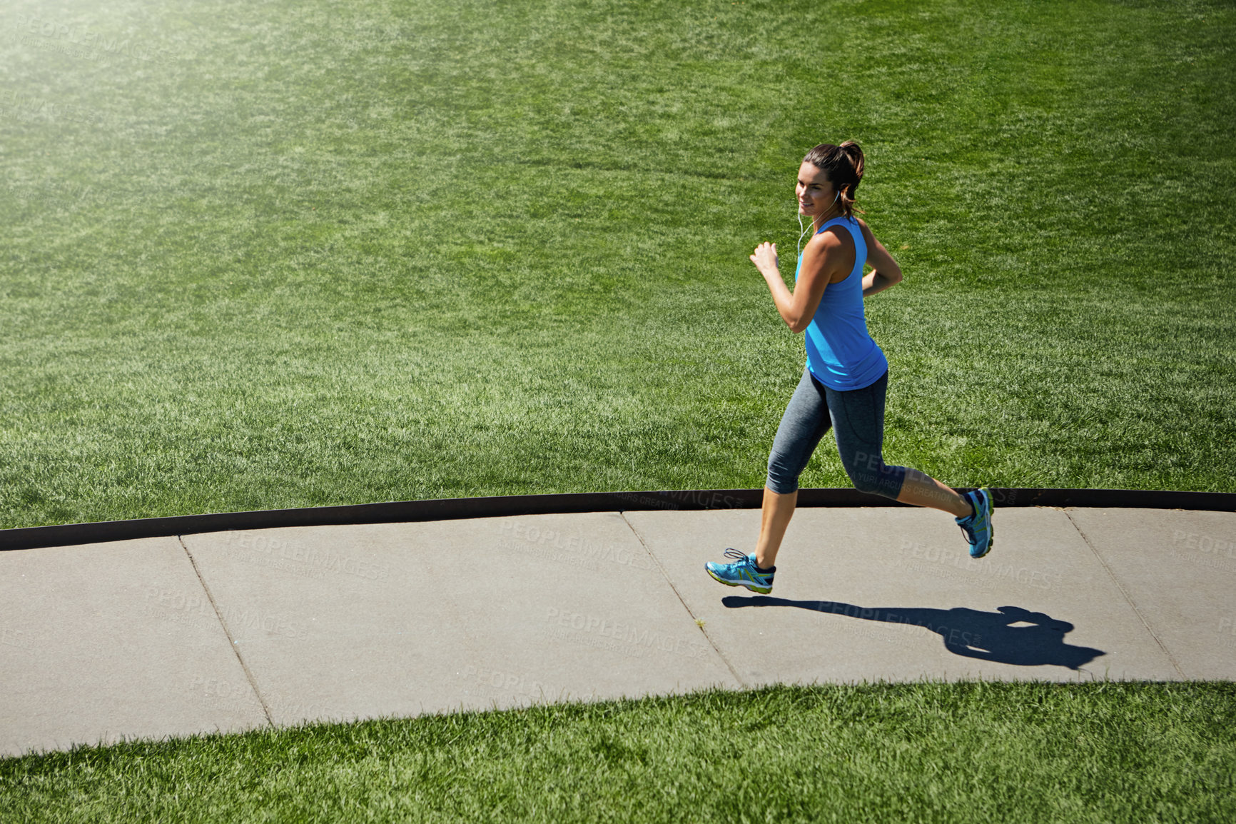 Buy stock photo Shot of a young woman listening to music while out running