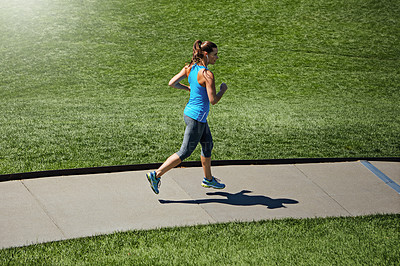 Buy stock photo Shot of a young woman listening to music while out running