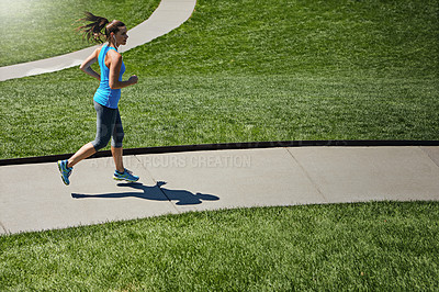 Buy stock photo Shot of a young woman listening to music while out running